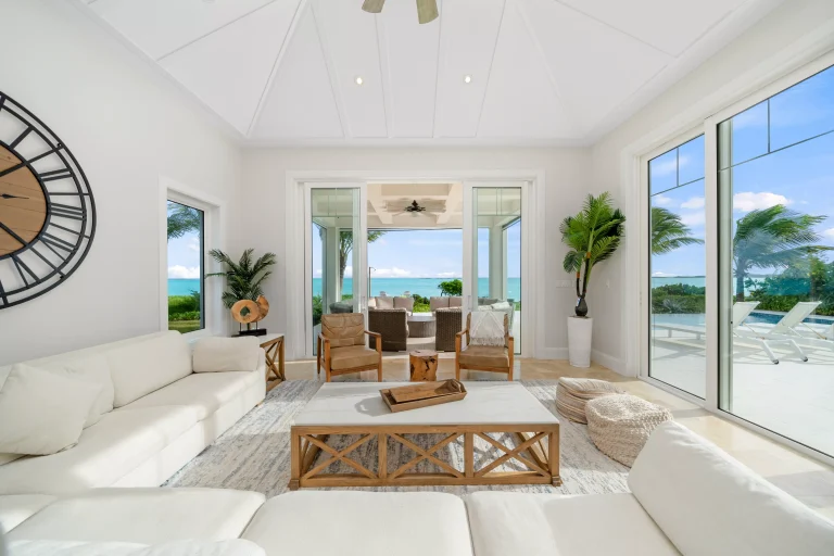 Living room with white sofas and wall clock at Seaclusion, George Town, Great Exuma