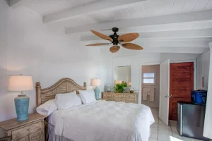 Bedroom with wooden headboard and fridge at Ocean Side Rooms, Hope Town, Elbow Cay