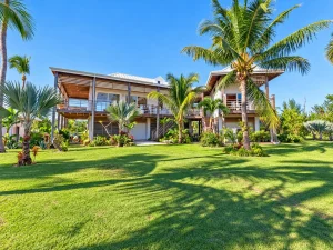 Two-story house with lawn and palm trees at Sea Smoke Estate, Treasure Cay, Abaco
