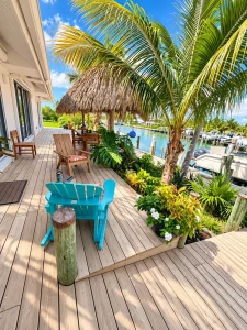 Deck with palm tree and tiki hut by the canal at Sea Smoke Estate, Treasure Cay, Abaco