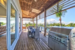 Covered deck with dining table and grill at Sea Smoke Estate, Treasure Cay, Abaco